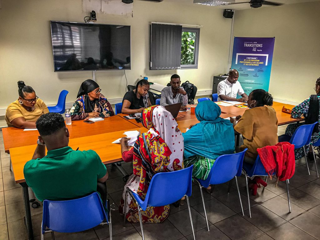 Salle de formation avec des personnes assises autour d'une table