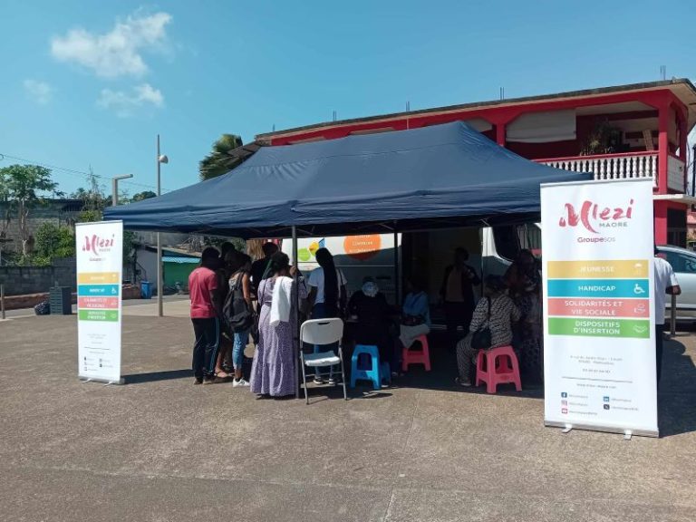 Ce mercredi 2 octobre, toutes les Maisons des Adolescents de France et d’outre-mer ont ouvert leurs portes au grand public puisqu’il s’agissait d’une initiative nationale. A Mayotte, la Maison des Adolescents est une structure de l’association M’lezi Maore, possédant ses propres locaux rue Soweto à Cavani. Etant donné que la rue est un peu retirée, l’association avait également disposé un camion d’accueil sur la place publique située devant le rond-point des P’tits loups, celui-là même qui lui sert à intervenir dans les différents villages de l’île. Si tout le monde pouvait venir découvrir la structure, M’lezi Maore avait également invité des groupes scolaires, dont beaucoup n’ont malheureusement pas pu être présents à cause de l’absence de bus ce mercredi, et plusieurs associations partenaires œuvrant dans des domaines similaires. « La Maison des Adolescents accueille les jeunes de 11 à 25 ans avec ou sans rendez-vous afin de les conseiller sur les différentes problématiques liées à l’adolescence », explique Ramlata Saïd, la cheffe de service de la structure. Santé sexuelle, addictions, décrochages scolaires, santé mentale, problèmes administratifs : le champ des thématiques abordées avec les professionnels de la structure présents pour écouter, conseiller ou orienter les adolescents se veut large. Deux éducateurs spécialisés, une assistante sociale, une animatrice et une infirmière travaillent pour la structure, mais l’association n’arrive malheureusement pas à recruter les deux psychologues et le pédopsychologue qu’il faudrait pour que l’équipe soit au complet. « Nous avons donc recours à des collaborations avec des professionnels en visio pour pallier ce manque », précise la cheffe de service. Objectif : que les jeunes « se saisissent de cet outil » Déplorant le fait que la Maison des Adolescents ne soit pas assez connue sur le territoire, Ramlata Saïd espère que les jeunes présents ce mercredi à la Journée Portes Ouvertes parviennent par la suite à « se saisir de cet outil ». Pour le moment, 15 jeunes par mois y sont suivis de manière individuelle et une vingtaine participent aux deux ateliers collectifs organisés par semaine, les mardi et mercredi après-midi. « Lors de ces ateliers, les professionnels abordent d’une manière ludique des thématiques précises comme la santé sexuelle, le mal-être ou le bien-être, l’IVG ou la notion d’engagement, par exemple », détaille la cheffe de service. Malgré l’exercice du droit de retrait des chauffeurs de bus scolaire, quelques jeunes venus des autres villages de Mayotte ont pu se rendre à Cavani pour découvrir la Maison des Adolescents. La plupart ne connaissaient pas cette structure, pourtant présente sur le territoire depuis 2010. D’où l’importance de renouveler chaque année ces journées portes ouvertes ! N.G