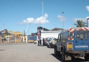Les forces de l'ordre devant l'entrée bloquée du port, avec  en arrière plan les grues installées par MCG