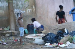 A deux pas du siège de Solidarité Mayotte, un enfant non surveillé se recouvre la tête d'un sac plastique au milieu des ordures