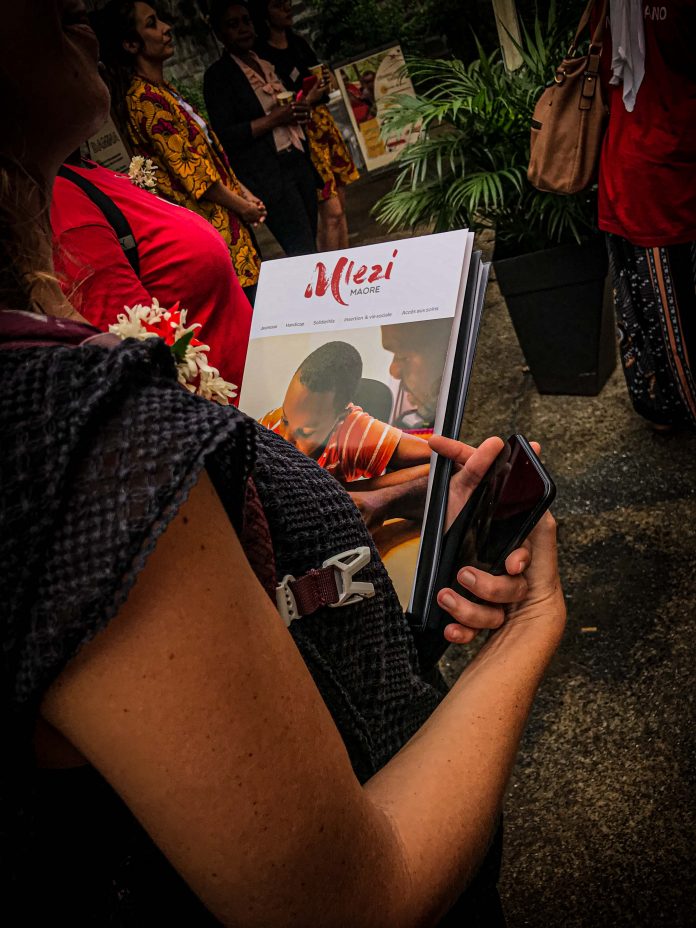 Femme portant une brochure de documentation de l'association Mlezi Maore