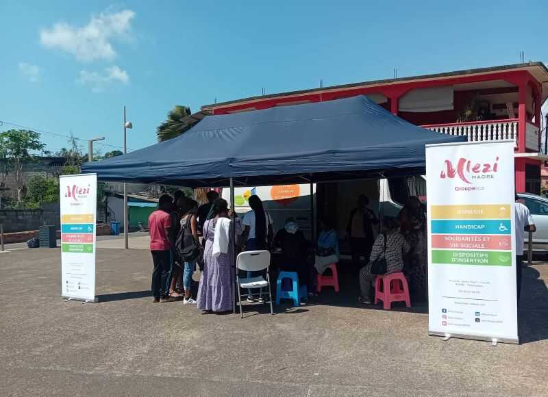 Ce mercredi 2 octobre, toutes les Maisons des Adolescents de France et d’outre-mer ont ouvert leurs portes au grand public puisqu’il s’agissait d’une initiative nationale. A Mayotte, la Maison des Adolescents est une structure de l’association M’lezi Maore, possédant ses propres locaux rue Soweto à Cavani. Etant donné que la rue est un peu retirée, l’association avait également disposé un camion d’accueil sur la place publique située devant le rond-point des P’tits loups, celui-là même qui lui sert à intervenir dans les différents villages de l’île. Si tout le monde pouvait venir découvrir la structure, M’lezi Maore avait également invité des groupes scolaires, dont beaucoup n’ont malheureusement pas pu être présents à cause de l’absence de bus ce mercredi, et plusieurs associations partenaires œuvrant dans des domaines similaires. « La Maison des Adolescents accueille les jeunes de 11 à 25 ans avec ou sans rendez-vous afin de les conseiller sur les différentes problématiques liées à l’adolescence », explique Ramlata Saïd, la cheffe de service de la structure. Santé sexuelle, addictions, décrochages scolaires, santé mentale, problèmes administratifs : le champ des thématiques abordées avec les professionnels de la structure présents pour écouter, conseiller ou orienter les adolescents se veut large. Deux éducateurs spécialisés, une assistante sociale, une animatrice et une infirmière travaillent pour la structure, mais l’association n’arrive malheureusement pas à recruter les deux psychologues et le pédopsychologue qu’il faudrait pour que l’équipe soit au complet. « Nous avons donc recours à des collaborations avec des professionnels en visio pour pallier ce manque », précise la cheffe de service. Objectif : que les jeunes « se saisissent de cet outil » Déplorant le fait que la Maison des Adolescents ne soit pas assez connue sur le territoire, Ramlata Saïd espère que les jeunes présents ce mercredi à la Journée Portes Ouvertes parviennent par la suite à « se saisir de cet outil ». Pour le moment, 15 jeunes par mois y sont suivis de manière individuelle et une vingtaine participent aux deux ateliers collectifs organisés par semaine, les mardi et mercredi après-midi. « Lors de ces ateliers, les professionnels abordent d’une manière ludique des thématiques précises comme la santé sexuelle, le mal-être ou le bien-être, l’IVG ou la notion d’engagement, par exemple », détaille la cheffe de service. Malgré l’exercice du droit de retrait des chauffeurs de bus scolaire, quelques jeunes venus des autres villages de Mayotte ont pu se rendre à Cavani pour découvrir la Maison des Adolescents. La plupart ne connaissaient pas cette structure, pourtant présente sur le territoire depuis 2010. D’où l’importance de renouveler chaque année ces journées portes ouvertes ! N.G